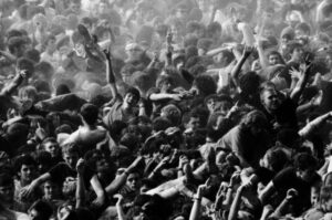 Dicht gedrängte Konzertmenge mit erhobenen Armen im Moshpit