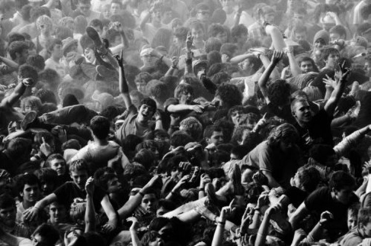 Dicht gedrängte Konzertmenge mit erhobenen Armen im Moshpit