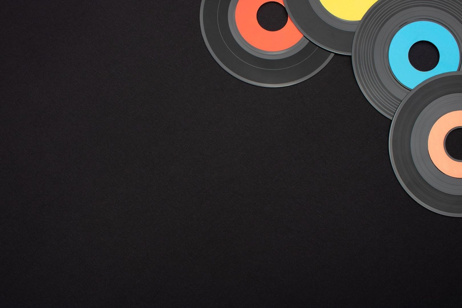 Mehrere farbige Schallplatten liegen auf schwarzem Hintergrund